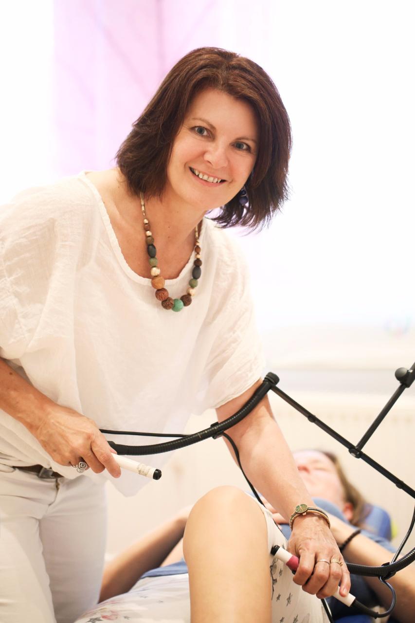 Barbara Schütz behandelt mit einem Elektrotherapie-Gerät das Knie einer Patientin